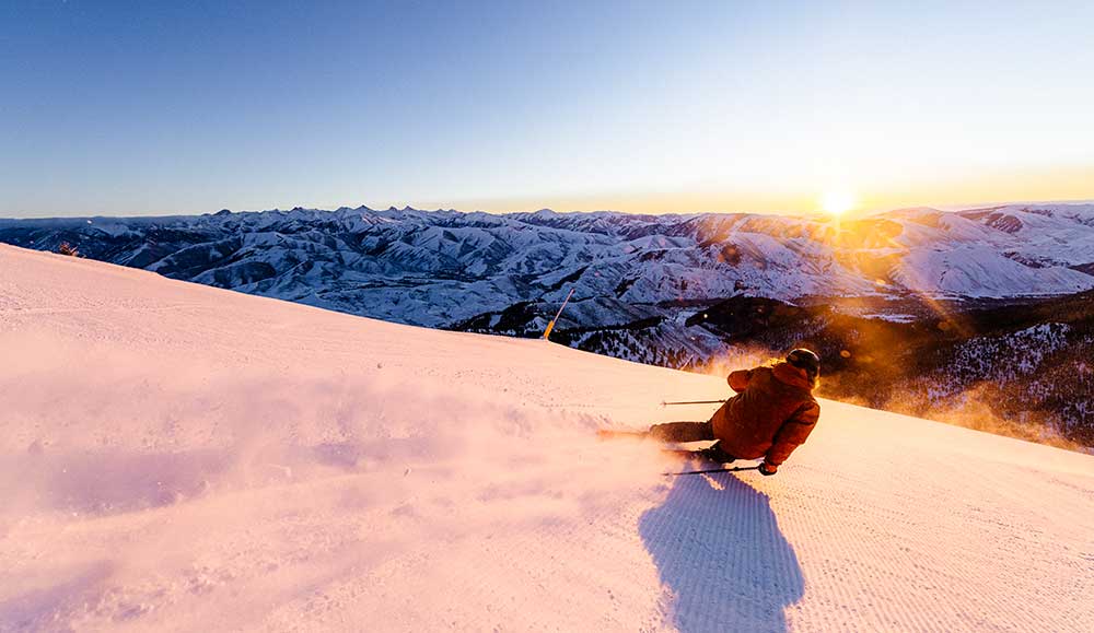 A skier at dawn rides a groomed run at Sun Valley