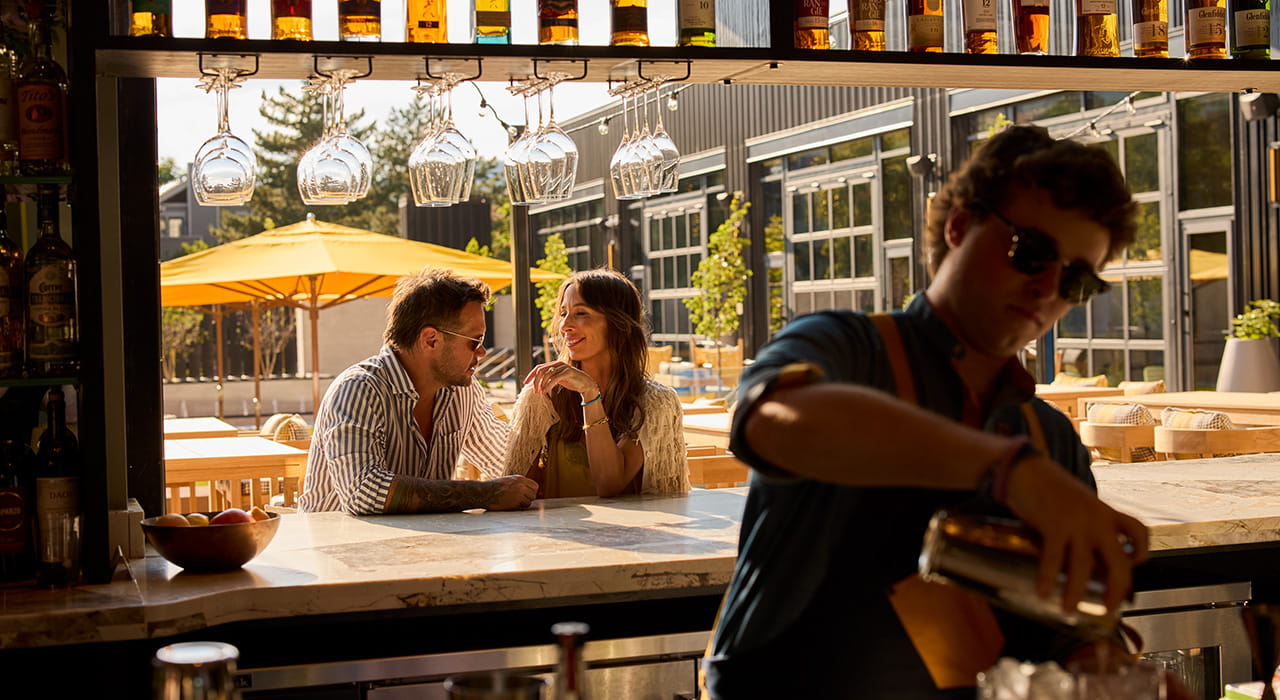 bartender making drink for couple at outdoor bar
