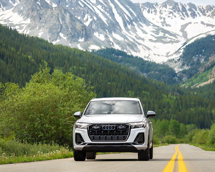 audi car driving on road in front of mountains
