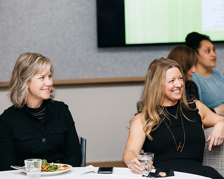 two women sitting down smiling