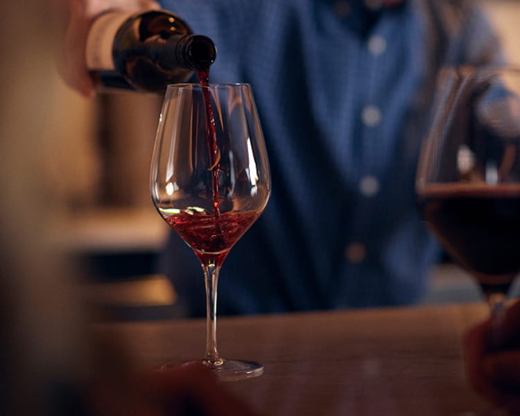 person pouring wine into glass