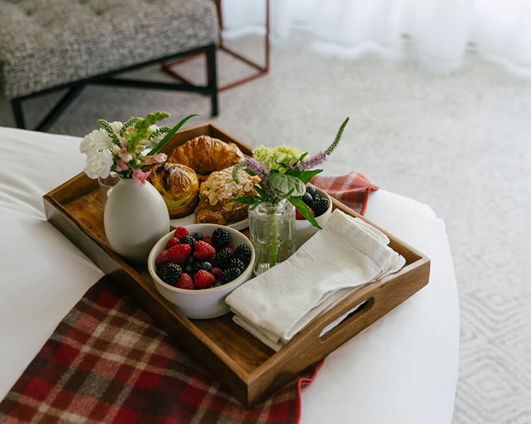 tray of breakfast food on bed