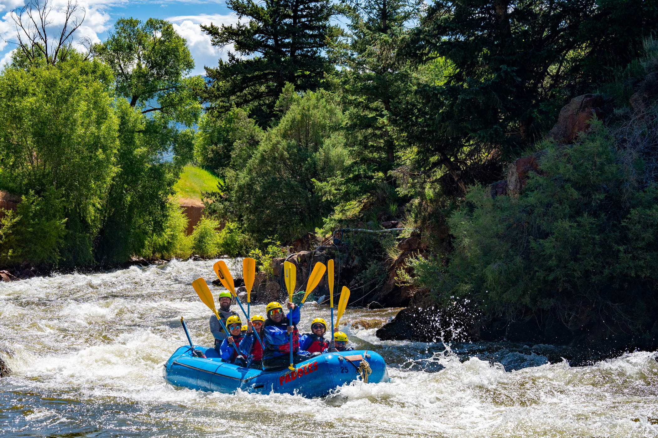 People white water rafting on a blue raft