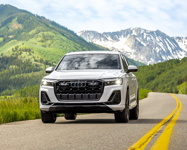audi car driving on road in front of mountains