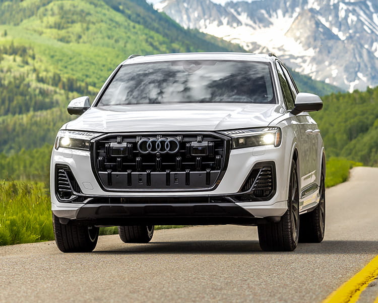 audi car driving on road in front of mountains