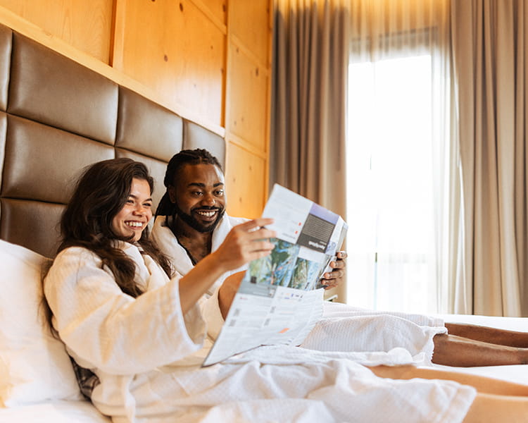 two guests on room bed smiling