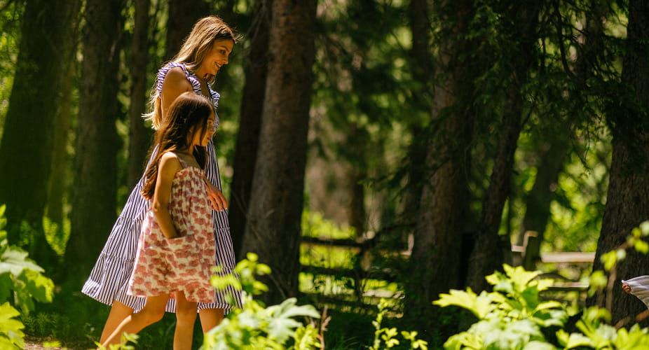 mother and daughter walking through forest