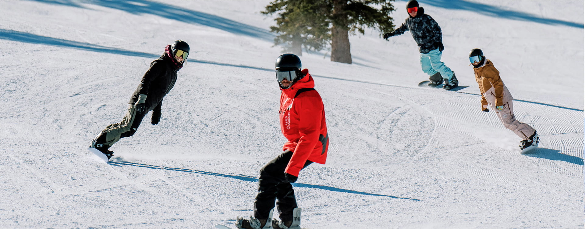 snowboarders riding down run during lesson