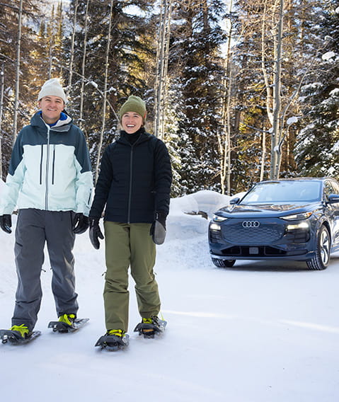 couple snowshoeing near audi car