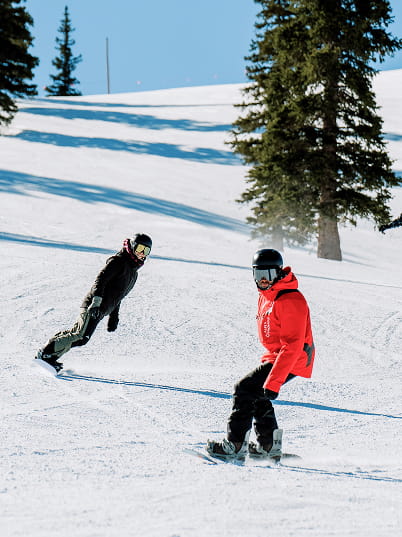 snowboard instructor and snowboarder going down mountain