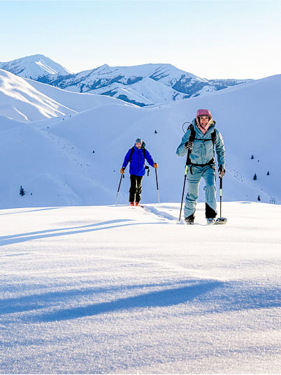 two backcountry skiiers skinning up mountain