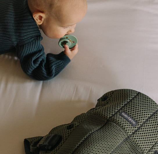 baby and carrier on bed