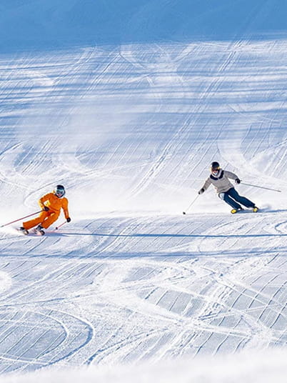 two skiers skiing down run