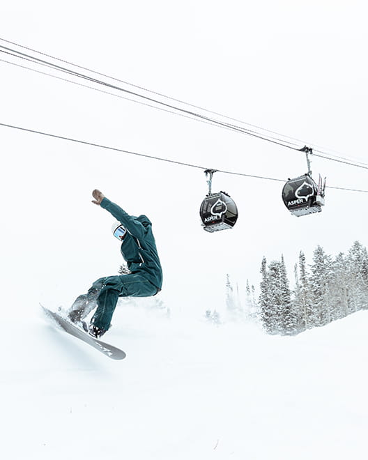 Snowboarder skiing under Aspen gondola