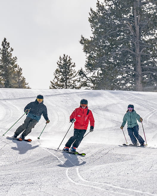 ski instructor with two skiers on aspen mountain