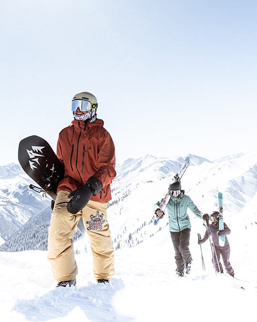 three skiers hiking up mountain