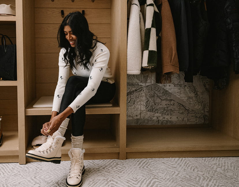 woman putting on boots in hotel room