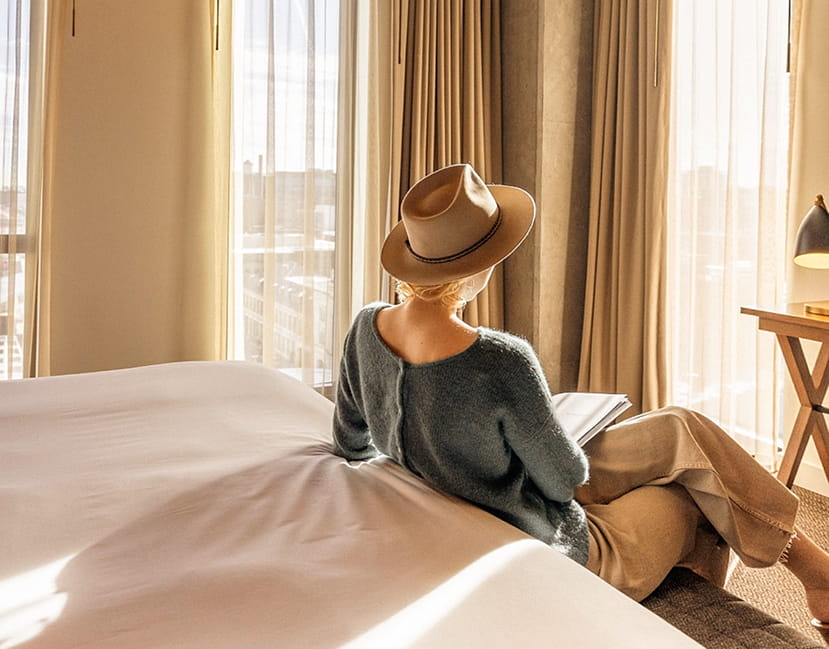 woman sitting next to bed in guestroom