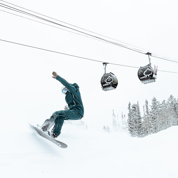Snowboarder skiing under Aspen gondola