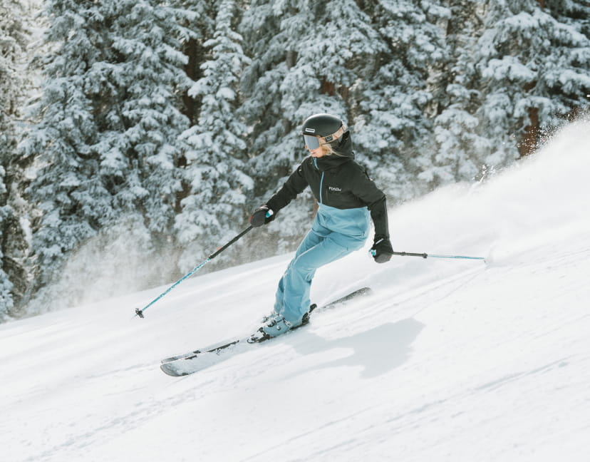 Skier in blue and black outfit skiing down a slope in winter