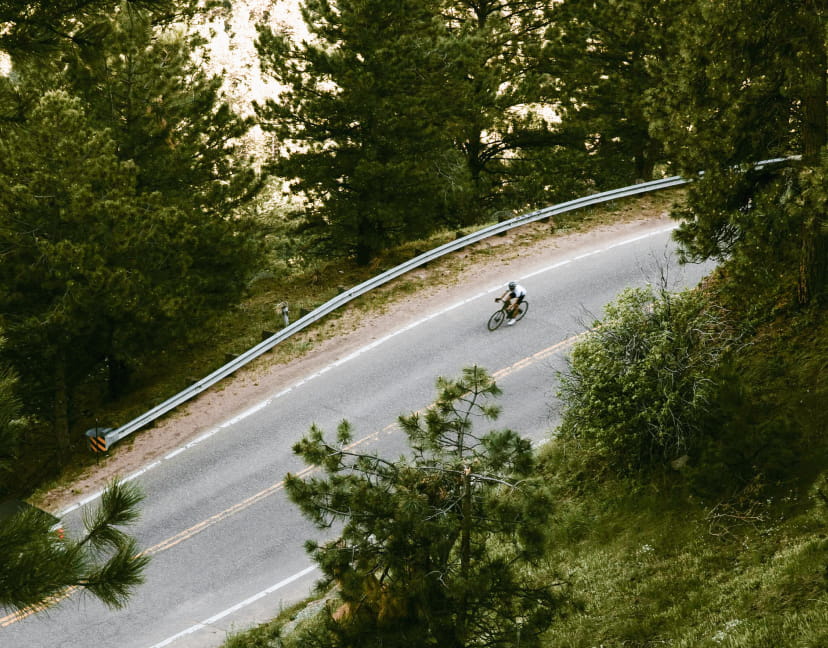 Cyclist on an empty road biking through trees