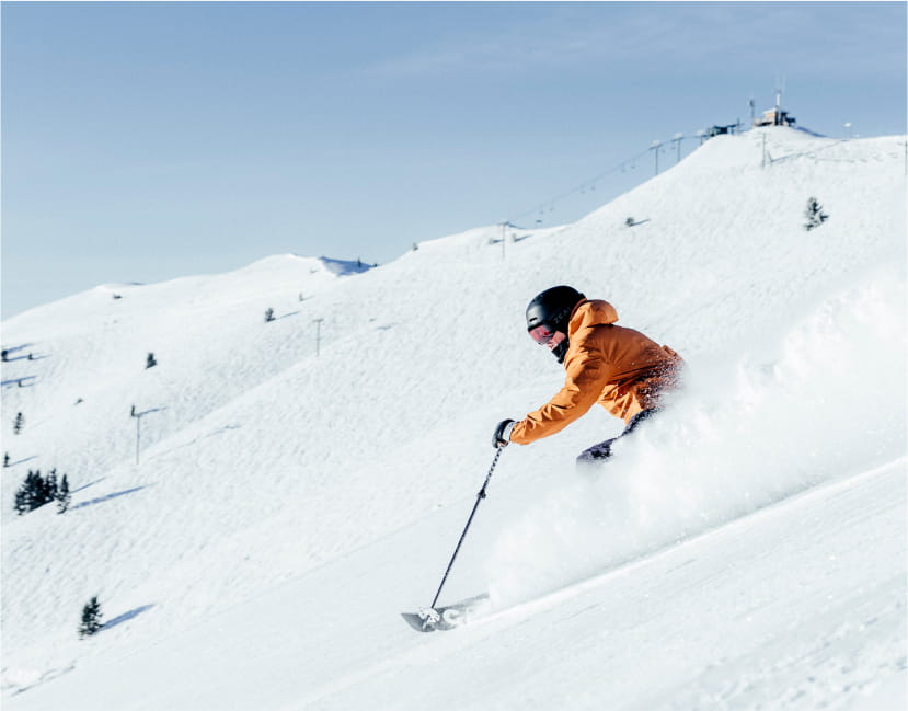 Skier in powder on a blue sky day at a ski resort