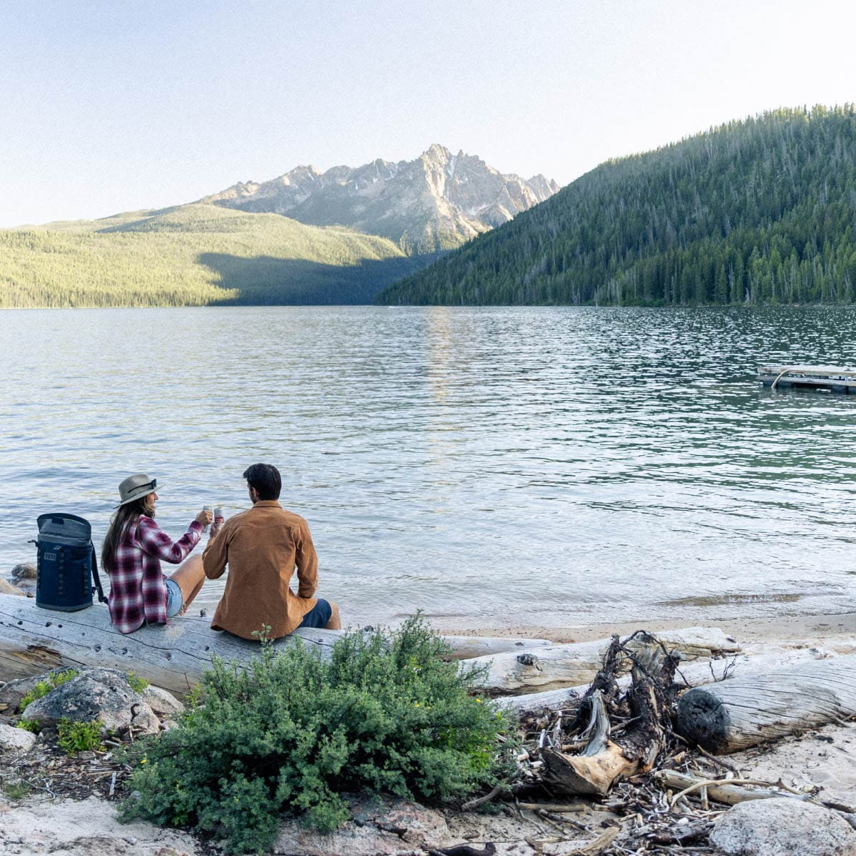 couple sitting by lake and mountains