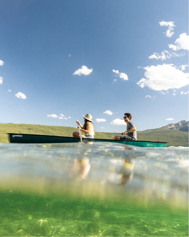 people canoeing on lake in mountain 
