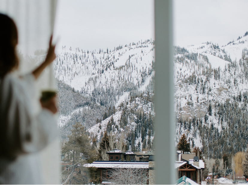 woman looking out window in hotel room at mountains