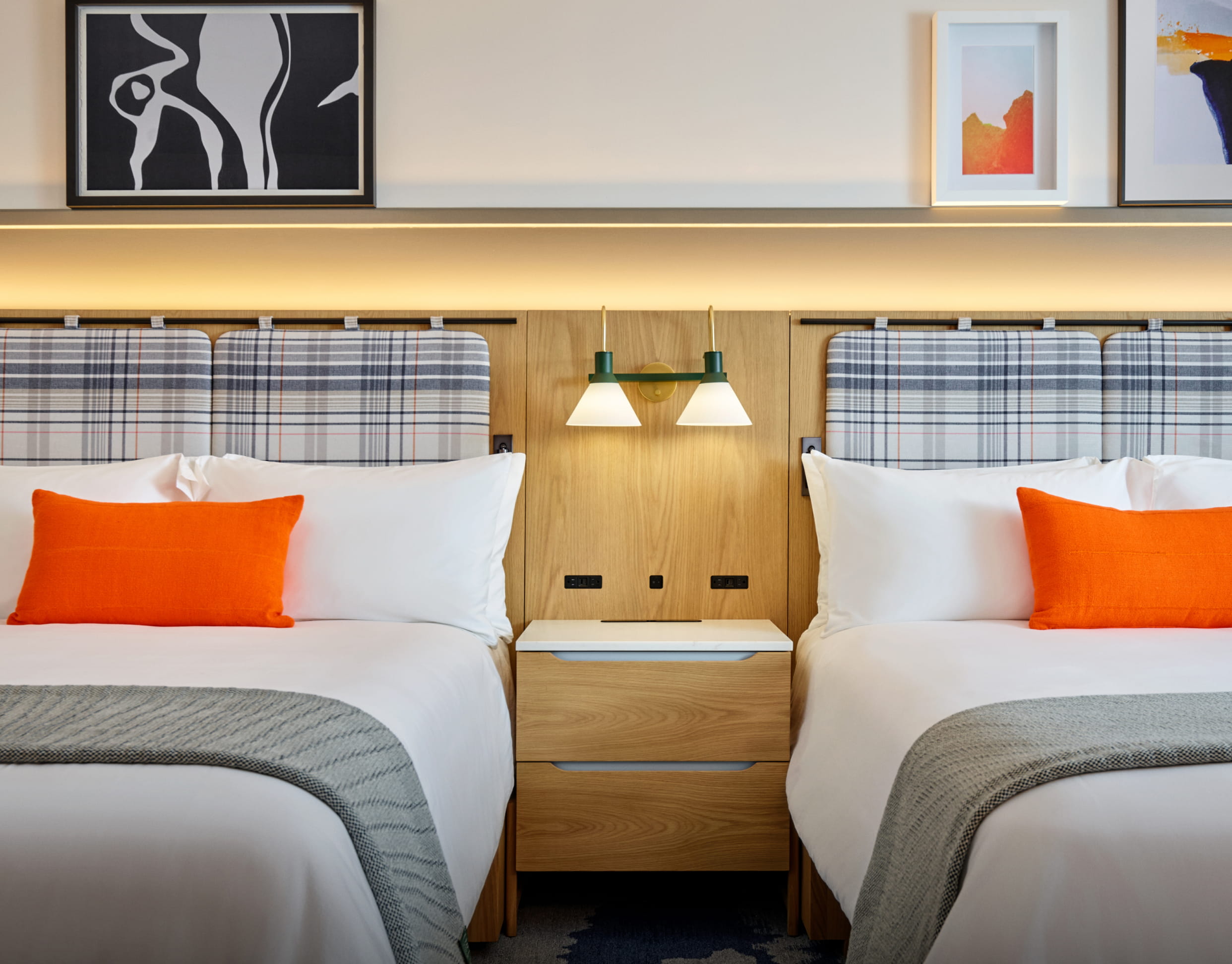 Photo of two queen beds in a hotel room with orange pillows