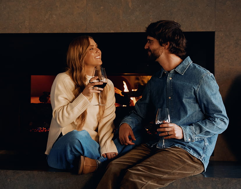 couple having wine by lounge fireplace