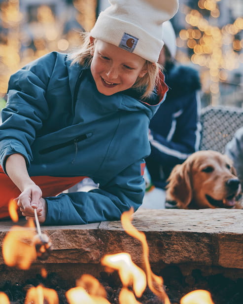 kid roasting marshmellows by outdoor fire pit