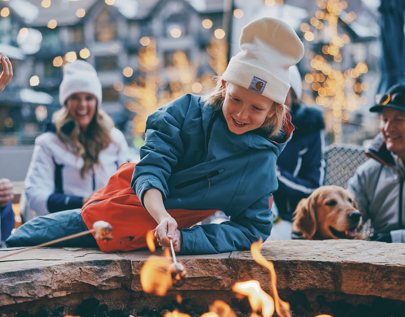 kid roasting marshmellows by outdoor fire pit