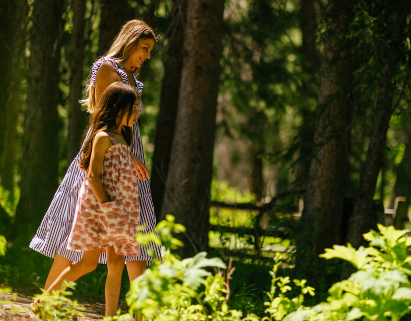 mother and daughter walking through forest