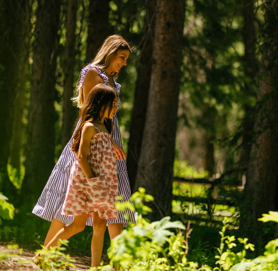 child walking with mother in forest
