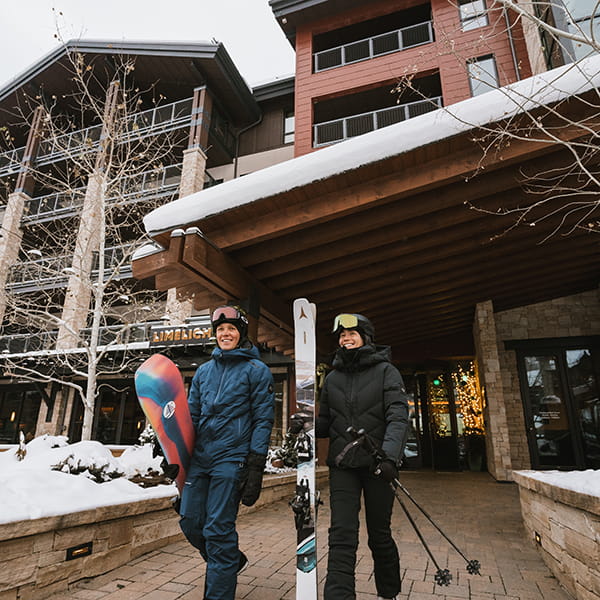 two people walking out of limelight snowmass to ski