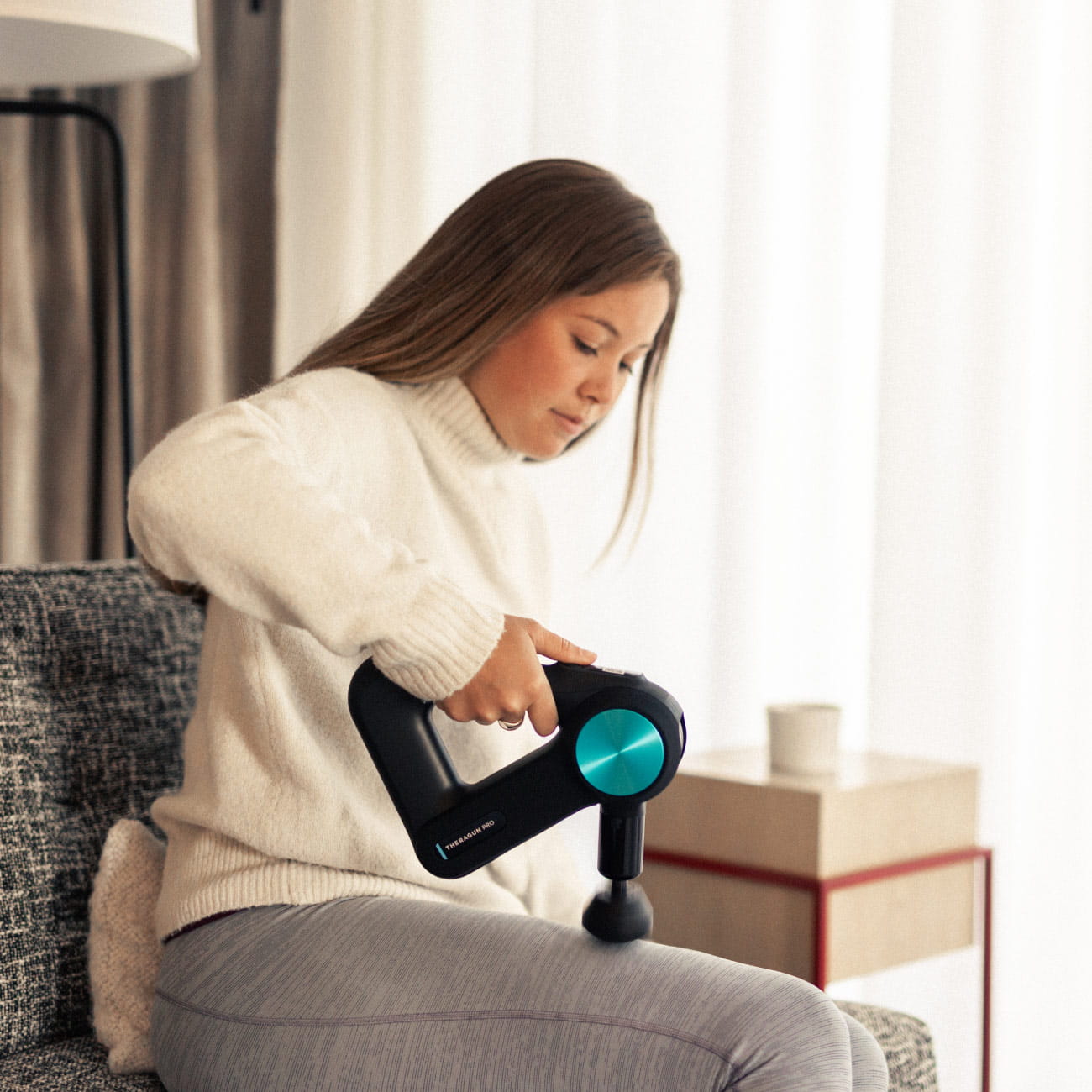 woman using theragun on leg