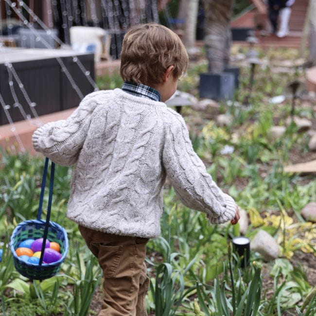 Child running in the grass collecting easter eggs in a basket