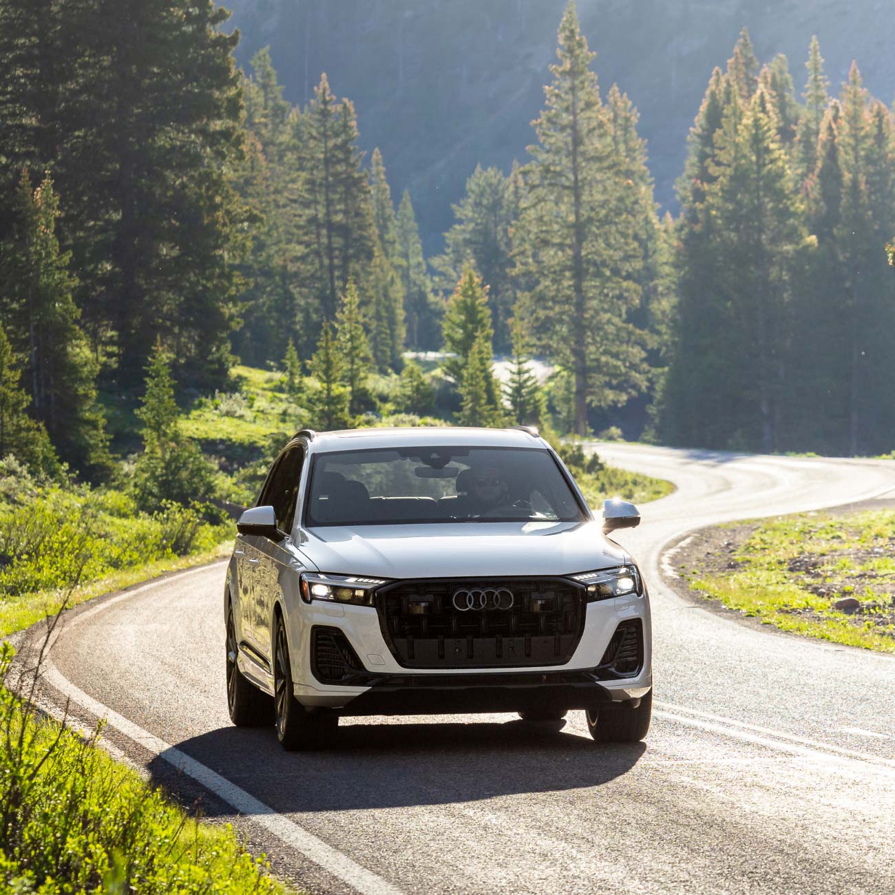 audi car driving on road in front of mountains