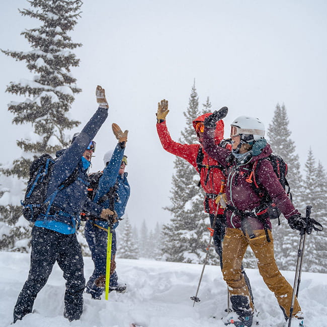 four backcountry skiers high-fiving