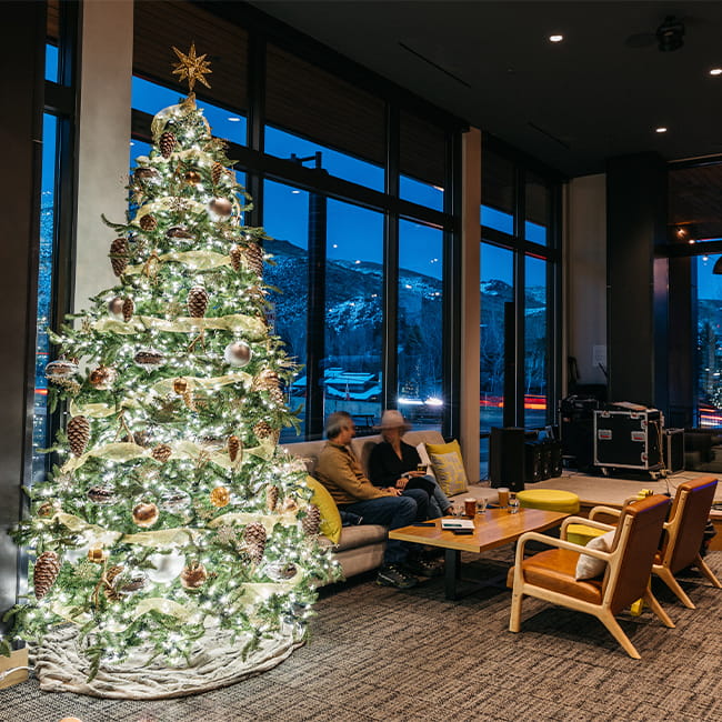 Christmas tree in a hotel lobby with a couple sitting on a couch