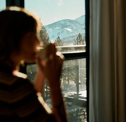 woman looking at mountains from room