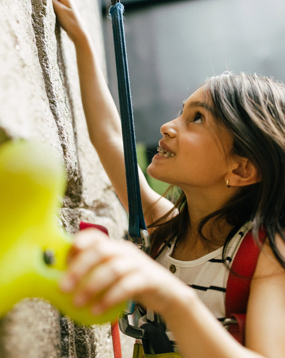 A child braces climbs a rock wall indoors. This wall is within Limelight Hotel in Snowmass, Colorado.