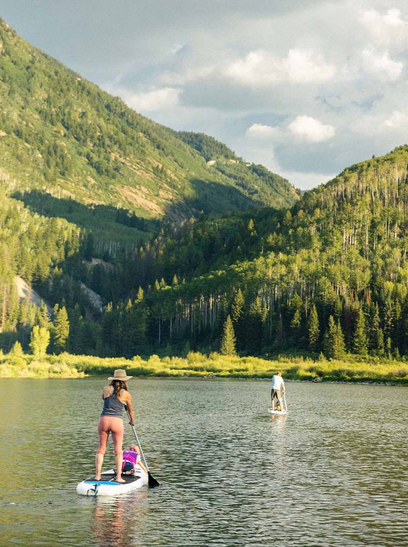two people paddleboarding on alpine lake