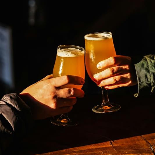 Two people cheersing with beer in glasses