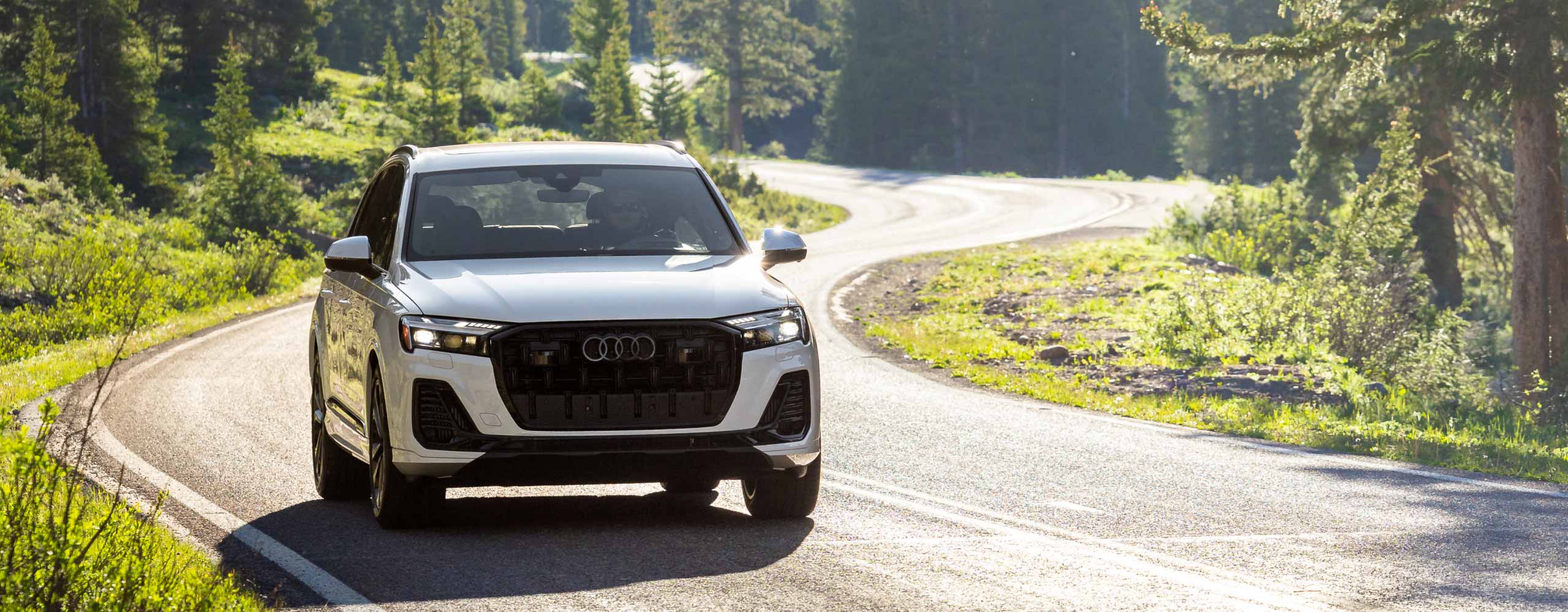 audi car driving on road in front of mountains