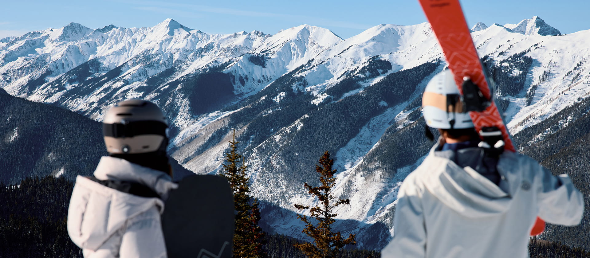 two skiers staring at the top of aspen mountains