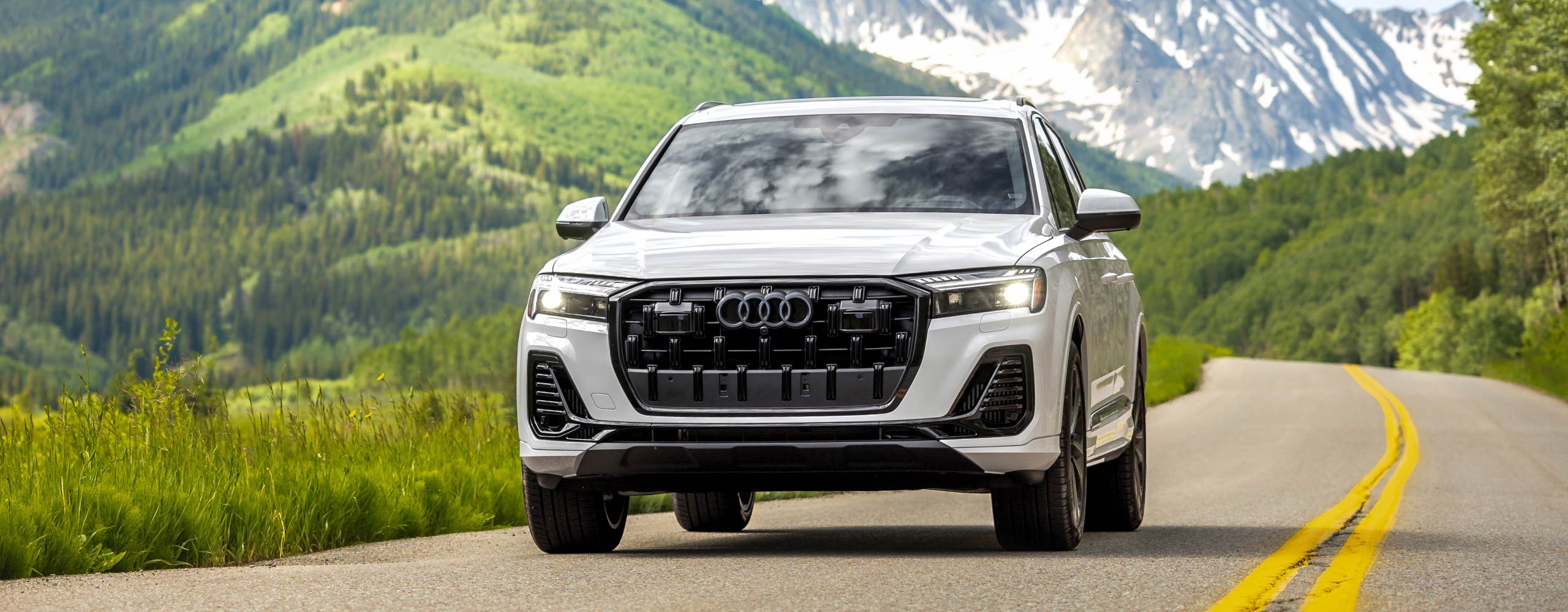 audi car driving on road in front of mountains