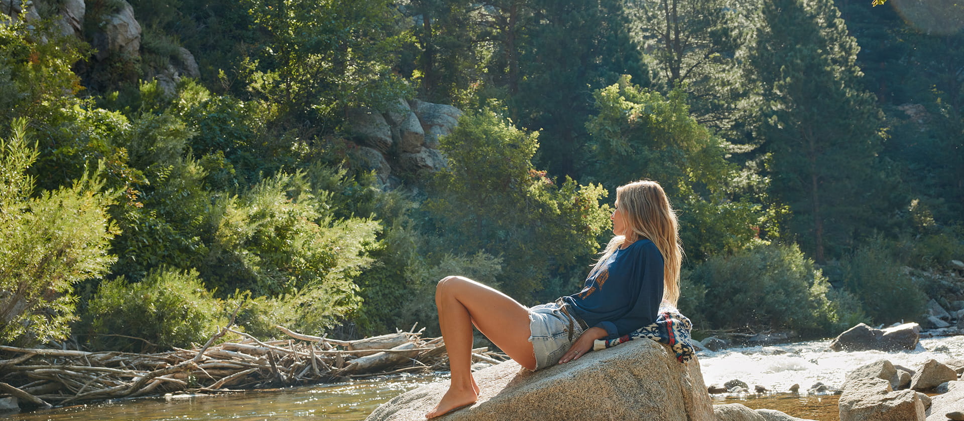 woman sitting on rock by river