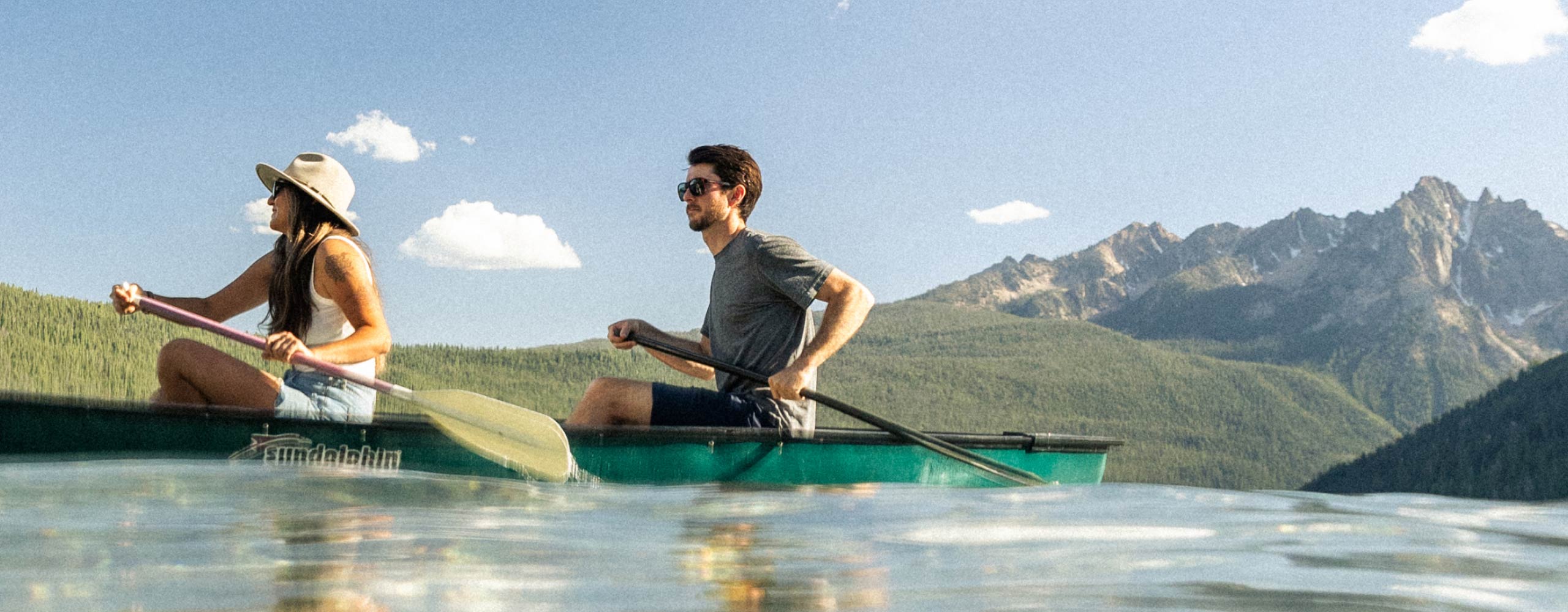 people canoeing on lake in mountain 